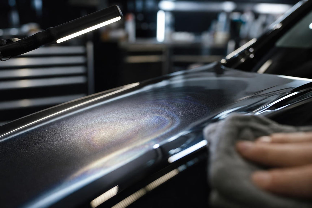 Inspectielamp toont een waasachtige high spot in keramische coating op een donker autodeel.