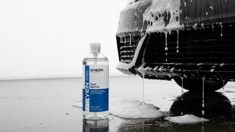 Gyeon Q2M Bathe autoshampoo fles naast een emmer schuim bij een keramisch gecoate auto