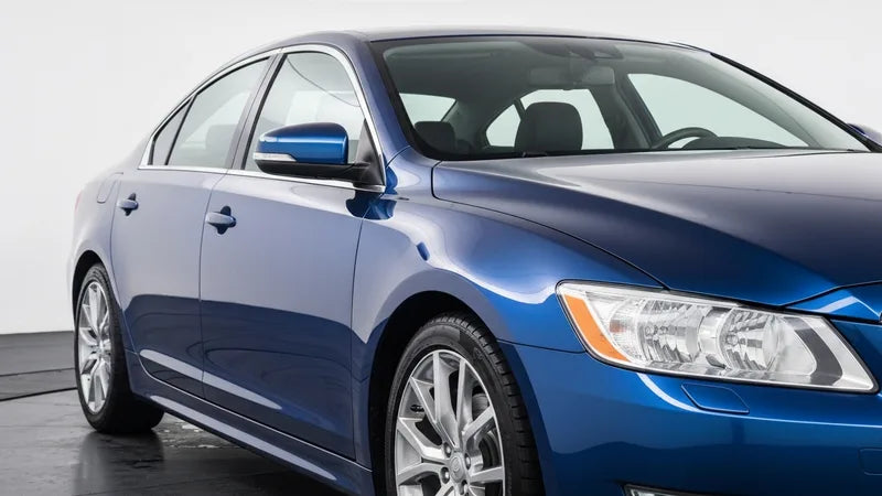 Fles Meguiar's Ultimate Liquid Wax naast een glanzende auto na het waxen in zonlicht