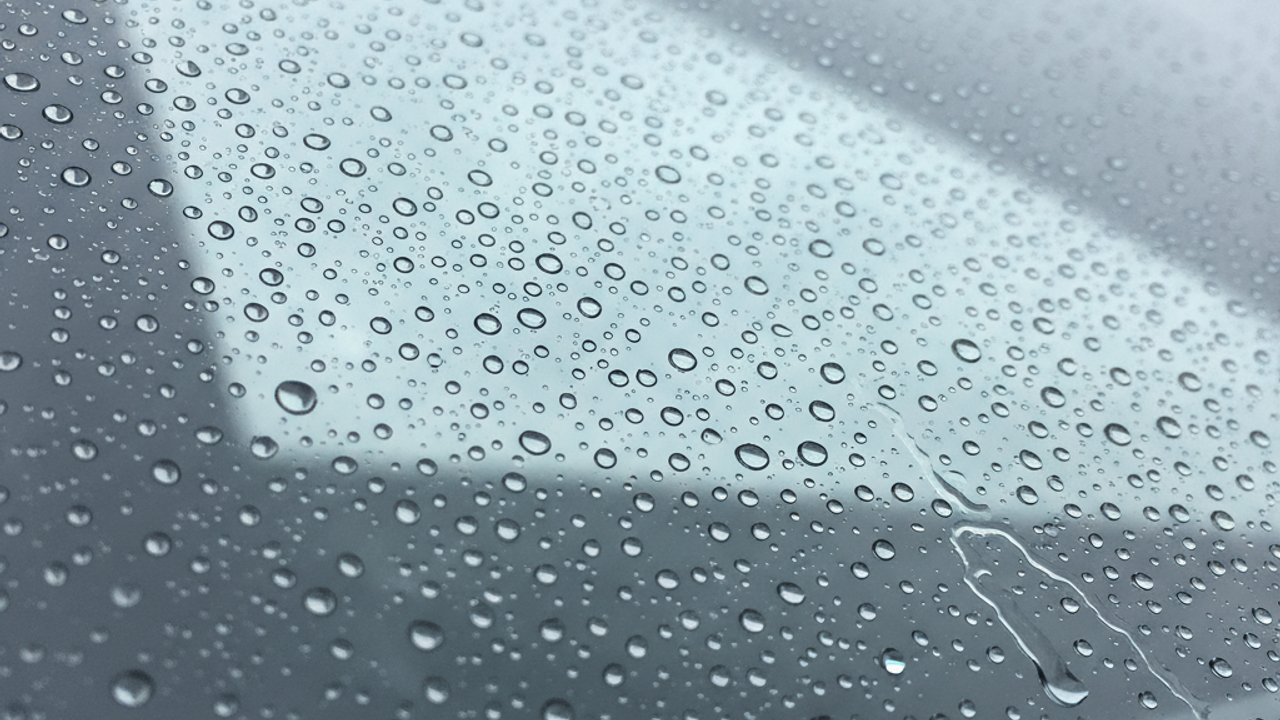 Waterdruppels die van een behandelde autoruit afrollen na aanbrengen regenafstoting auto